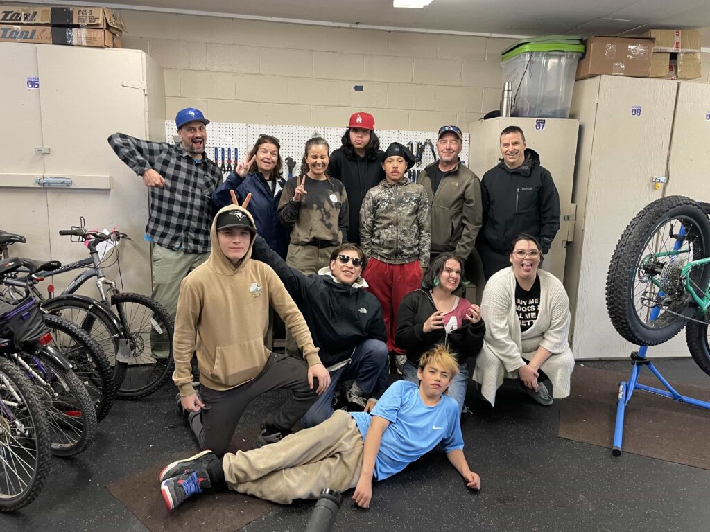 Group of indigenous youth and community volunteers posing at community bike repair workshop